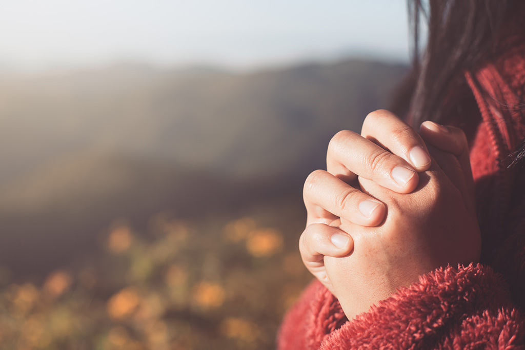 Women with tight clasp in prayer