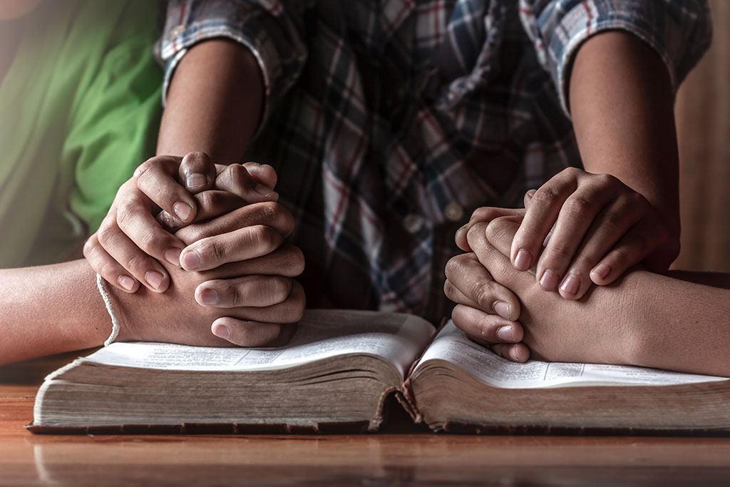 People holding hands in supportive prayer