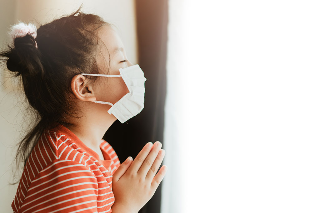 girl praying with mask on