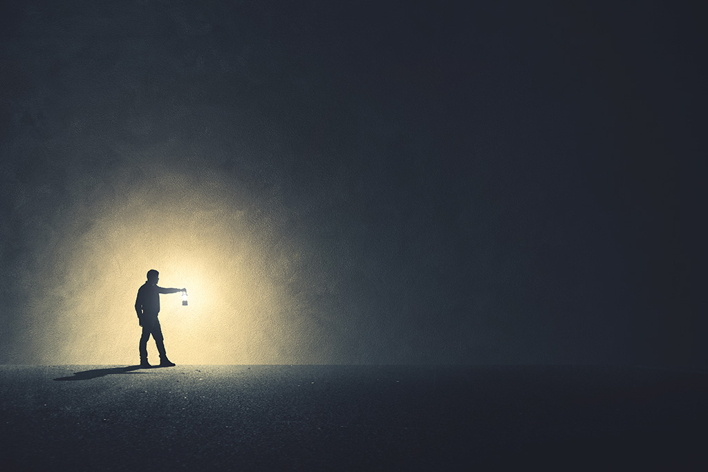 Man with lantern spreading light in the darkness