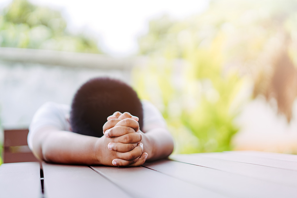 Boy praying with his head down.