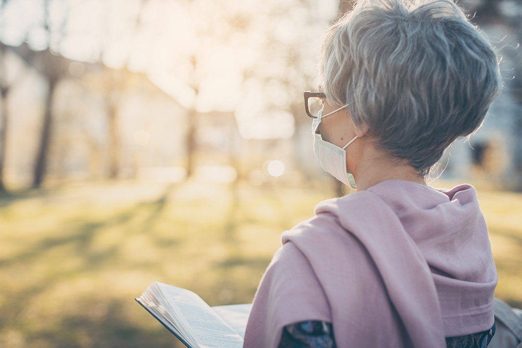 Woman reading Bible with mask on