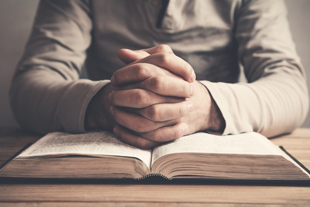 Man with hands clasped in prayer