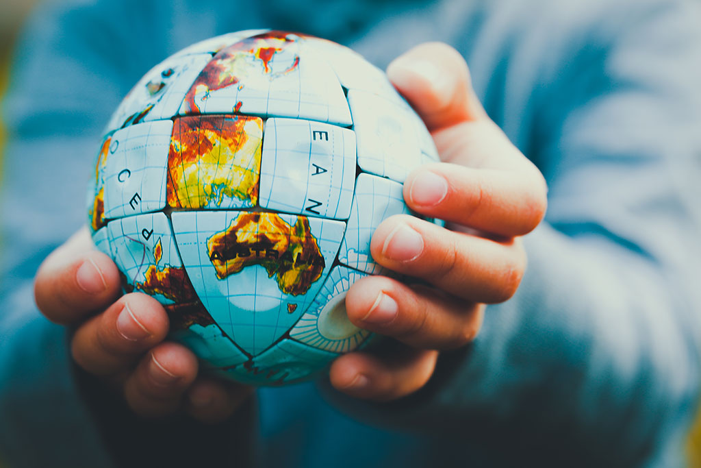 Person holding a globe that is messed up in his hands.
