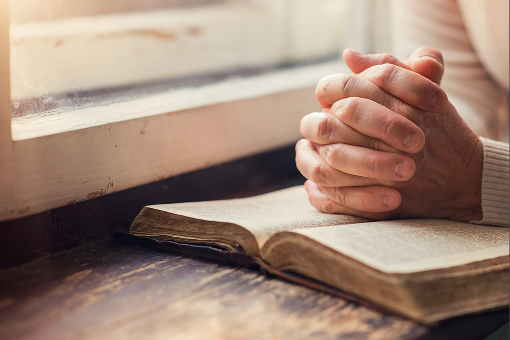 Hands clasped on a Bible